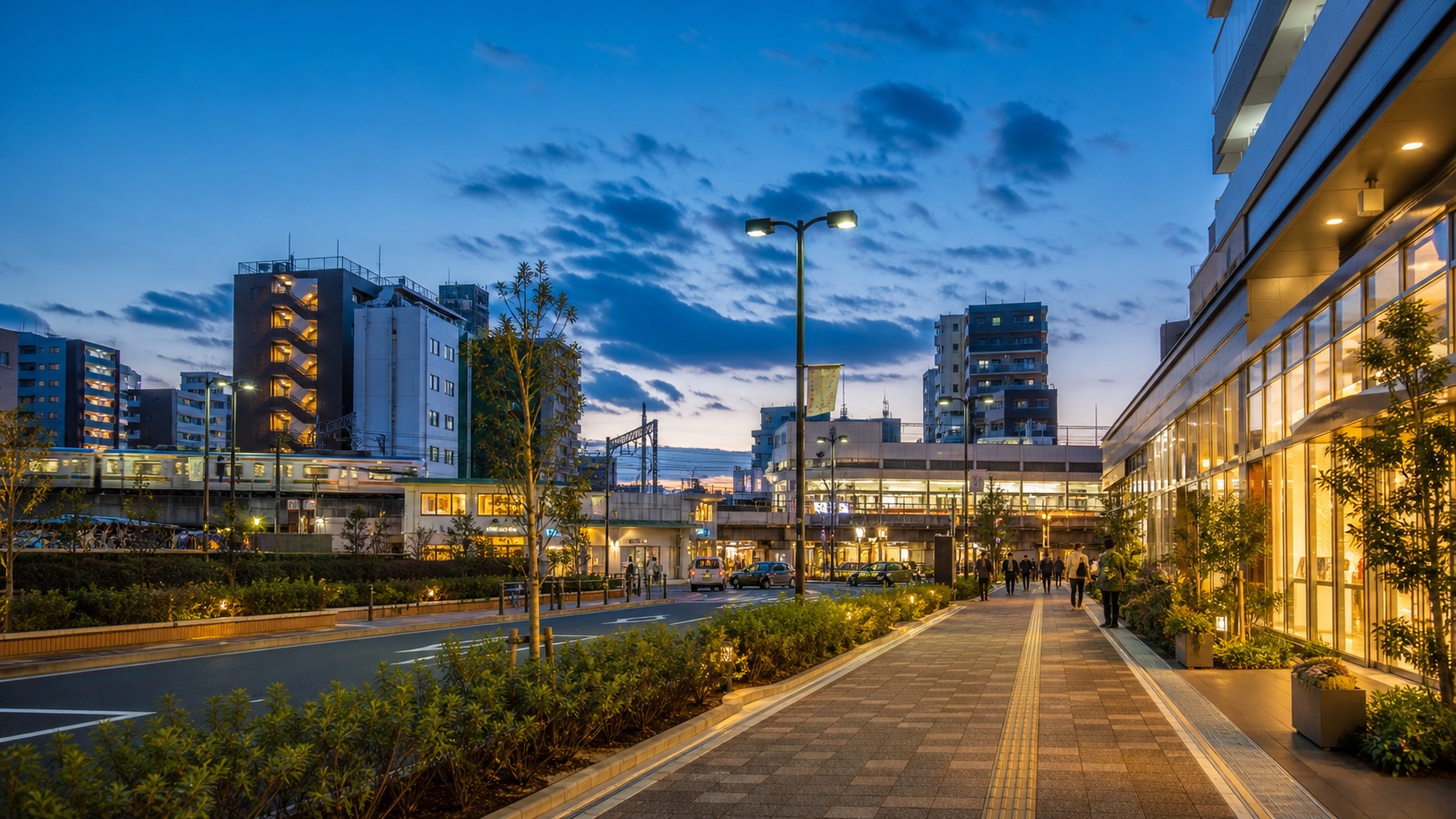 Oimachi station area at dusk with rail tracks, shops, and a pedestrian walkway