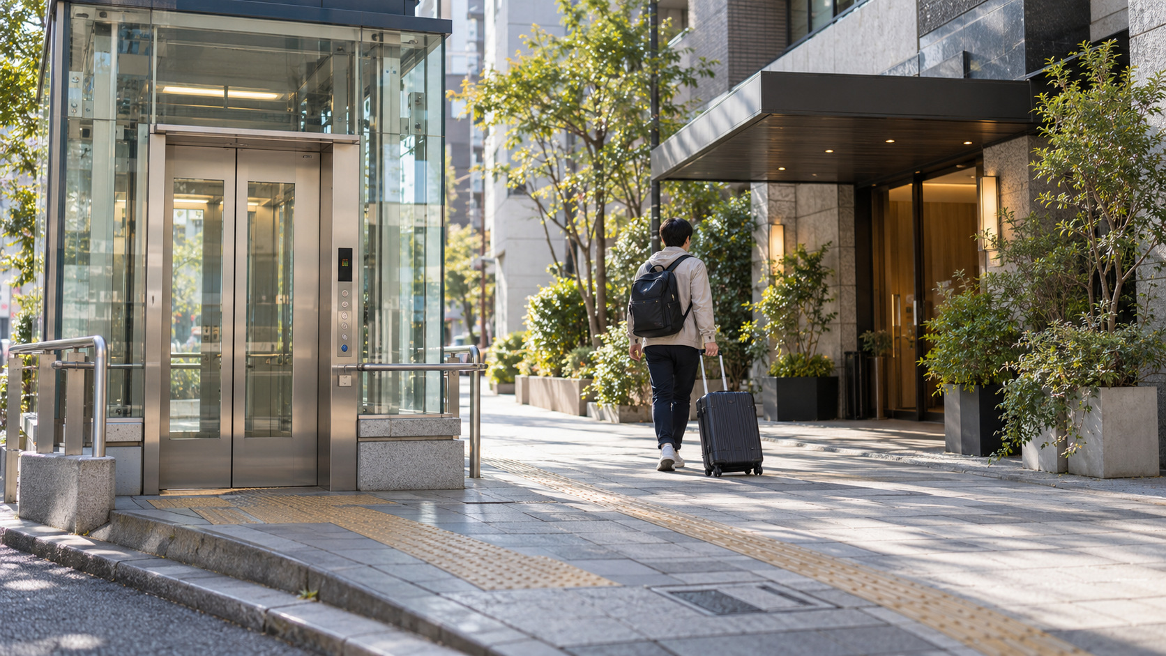 A traveler rolls a suitcase from a street-level subway elevator toward a nearby hotel entrance.