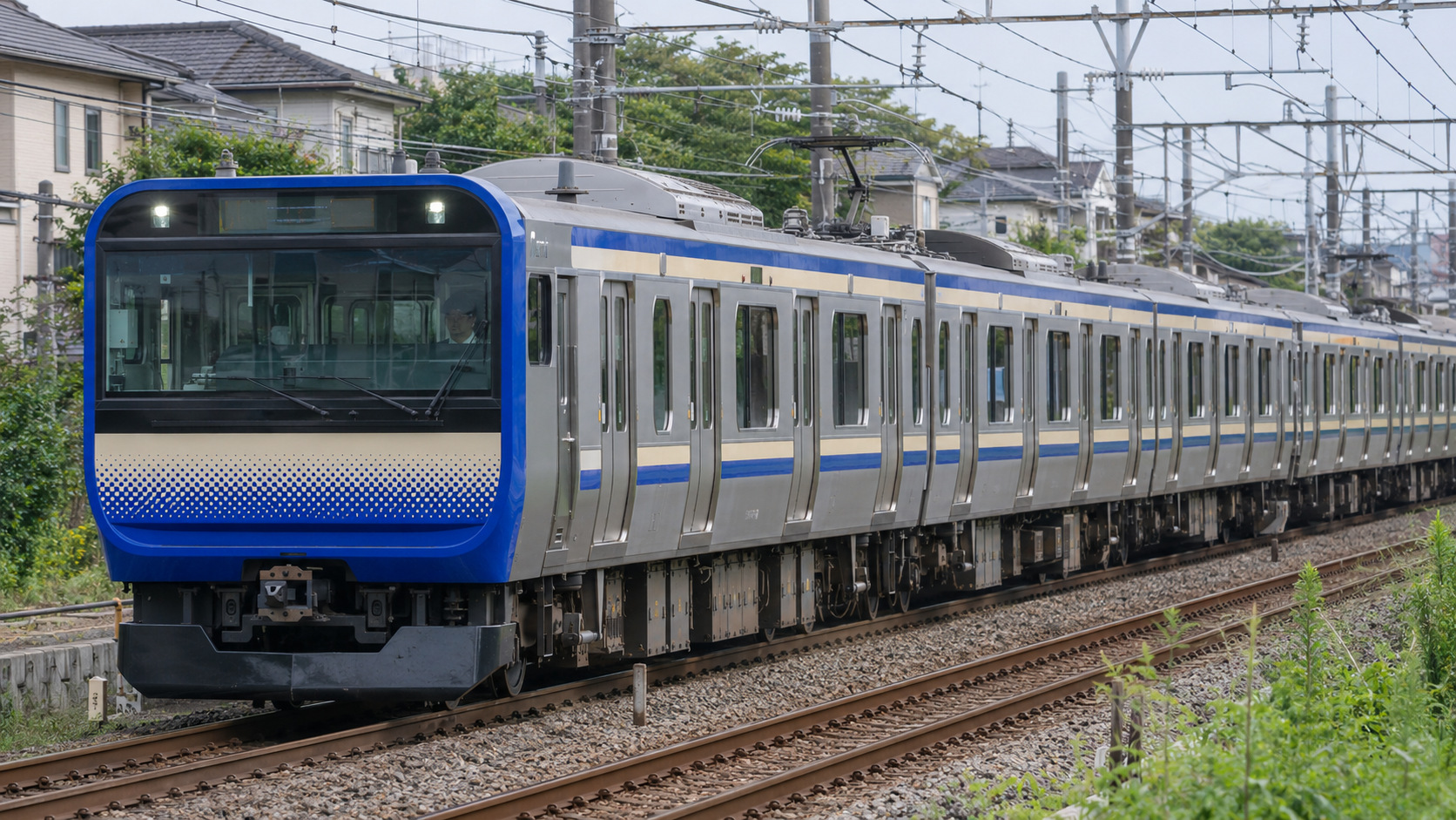 青とクリームの横須賀線・総武快速線E235系を、住宅と緑に囲まれた線路で描いた写真風画像。